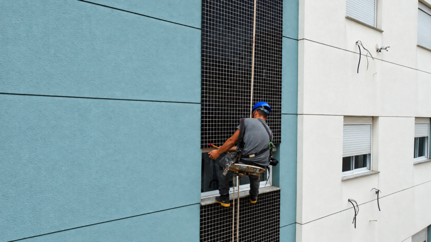 Profissional realizando inspeção por percussão em revestimento cerâmico de fachada de edifício